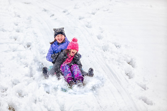 Friends tobogganing downhill
