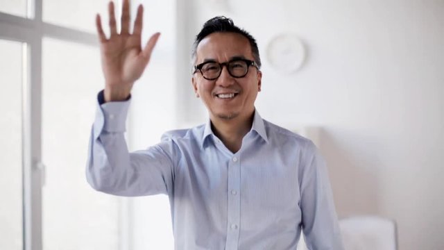 happy asian businessman waving hand at office