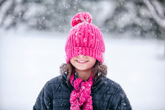 Girl with pink knitted hat pulled over eyes