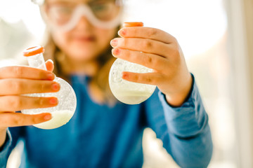 Girl doing science experiment, holding flasks of liquid