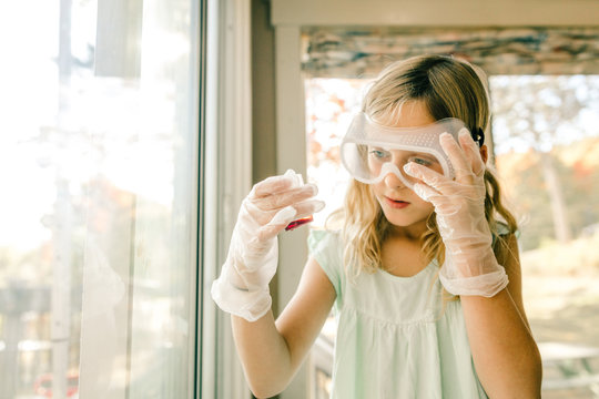 Girl doing science experiment, staring at measuring flask