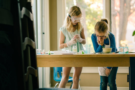 Two girls doing science experiment, reading chemistry set instructions