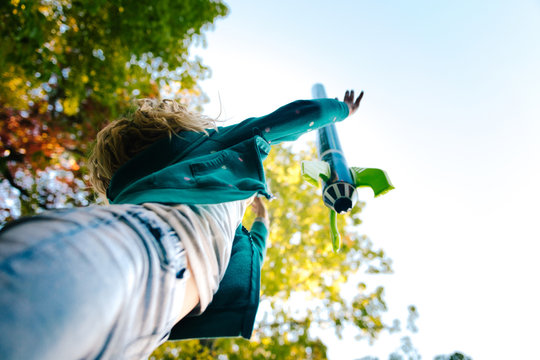 Low angle view of girl throwing toy rocket skyward from garden