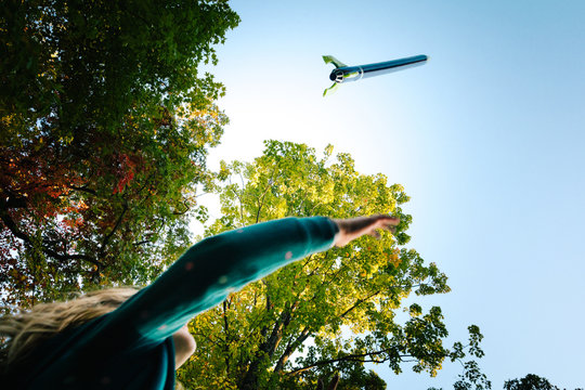 Low angle view of girl watching toy rocket flying toward blue sky