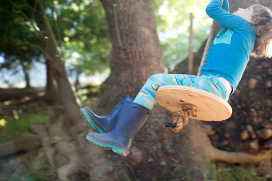 Young boy outdoors, swinging on rope swing