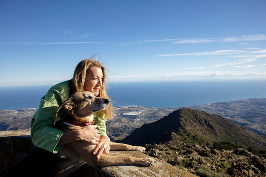 Mature woman and dog looking out from elevated view near coast, Estepona, Spain