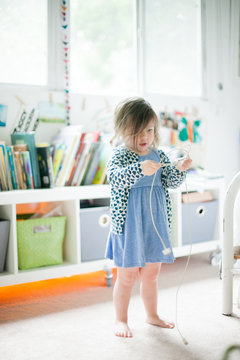 Girl standing in playroom untangling computer cable
