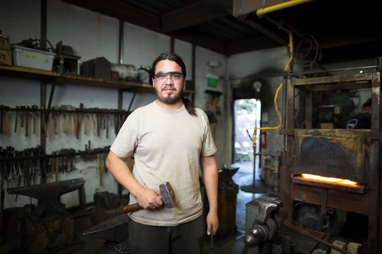 Portrait of male metalsmith by metal workshop furnace