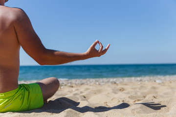 Guy meditating in sandy beach