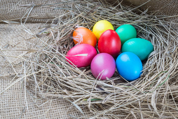 Colorful easter eggs in hay on sackcloth background