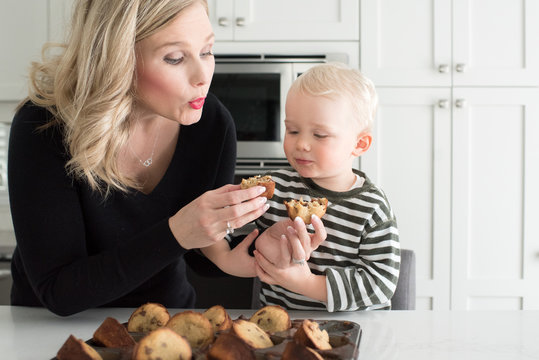 Mother and son in kitchen, breaking freshly baked cake, ready to taste