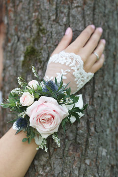 Pale pink, blue and green wrist corsage on a hand 