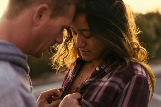 Man unfastening girlfriend's shirt at Newport Beach, California, USA