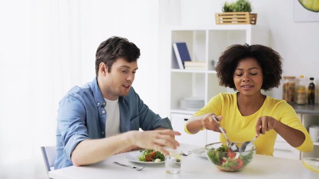 happy couple eating vegetable salad at home