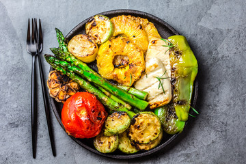 Grilled vegetables, pineapple and cheese on cast iron black plate