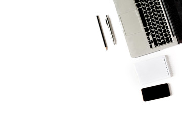 Empty copyspace in left corner and center. Minimalistic workplace with laptop keyboard, smartphone, notebook, pen and pencil on white background. Flat lay