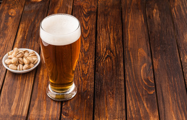glass of light cold frothy beer, nuts old wooden table