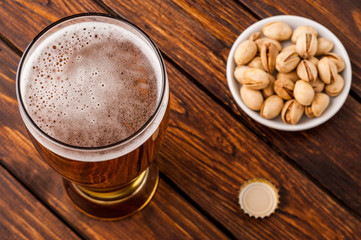 glass of light cold frothy beer, nuts old wooden table