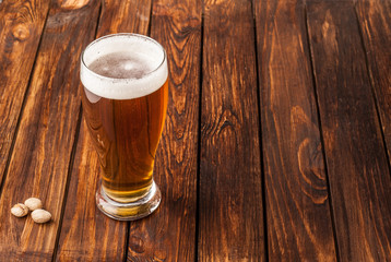 glass of light cold frothy beer, nuts old wooden table