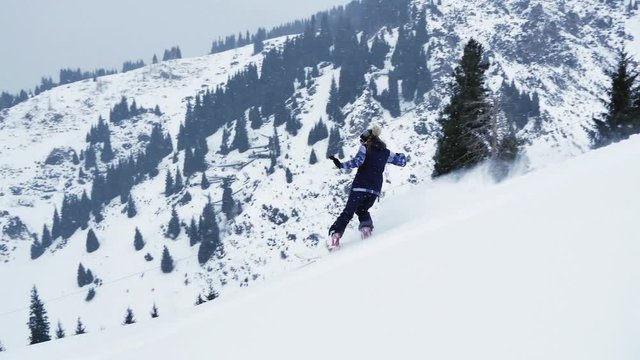 Extreme snowboarder woman riding by powder at mountain backcountry. Snowboarding, winter activities