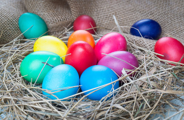Colorful easter eggs in hay on sackcloth background