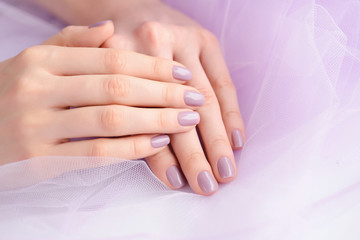 Closeup of hands of a young woman with pink manicure on nails against the background of a pink vei