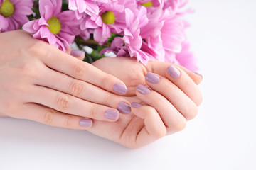 Hands of a woman with pink manicure on nails and pink flowers