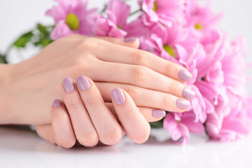 Hands of a woman with pink manicure on nails and pink flowers