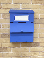 Blue mailbox on the yellow brick wall