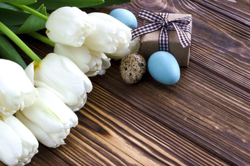 Bouquet white  tulip flowers with  easter eggs on wooden table. Place for your text. Easter background.