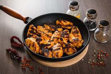 grilled chicken wings in grill panwith spices, wooden background