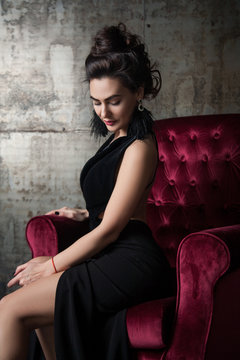 attractive woman sitting in a velvet armchair