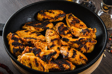 grilled chicken wings in grill panwith spices, wooden background