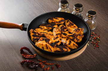 grilled chicken wings in grill panwith spices, wooden background