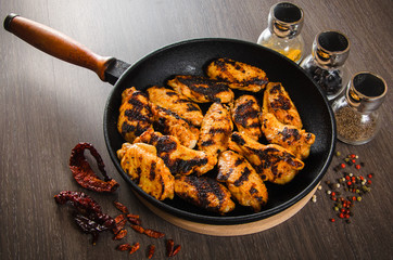 grilled chicken wings in grill panwith spices, wooden background