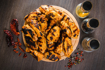 grilled chicken wings in grill panwith spices, wooden background