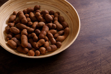 Sweet tamarind on grunge rustic wood background. Natural organic diet food with a lot of vitamins. Plate dish or bowl on wooden board.
