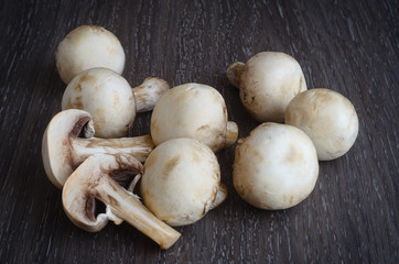 Fresh mushrooms champignons on wooden background.