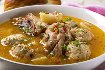 Meatballs soup with chicken meat and herbs in bowl