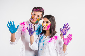Indian Couple showing their colored hands or with pichkari or sweet laddu on Holi festival,...