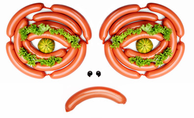 Angry face from sausages, lashes from salad, pupil mini pumpkin.Concept funny food.Food art.Food emotion