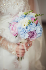 Wedding bouquet in pink and blue in the hands of the bride
