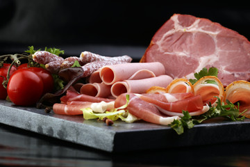 Food tray with delicious salami, pieces of sliced ham, sausage, tomatoes, salad and vegetable - Meat platter with selection