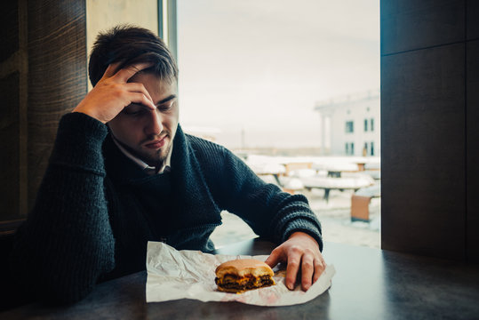 Portrait Of A Young Bearded Man Sitting In The Restaurant And Fast Food Can No Longer Eat