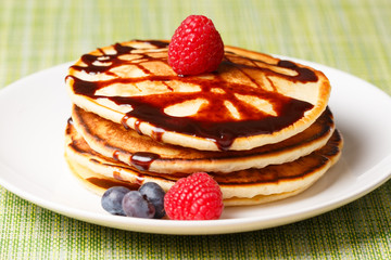 Pile of Pancakes with blueberries and raspberries and chocolate sauce