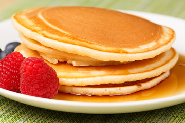 Pile of Pancakes with blueberries and raspberries and maple syrup