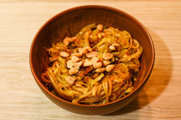 Chinese noodle with vegetables, peanuts and oyster sauce in clay bowl