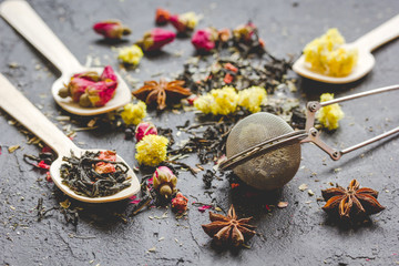 Tea herbs and spoons on grey background