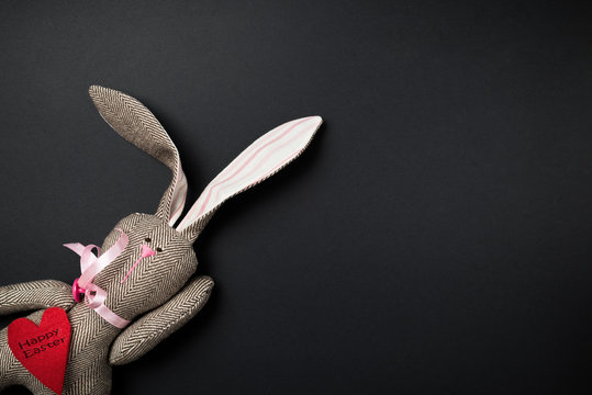 Easter bunny on a black background. Rabbit. Easter ideas. Easter eggs. Space for text. Black lettering on a heart happy easter.