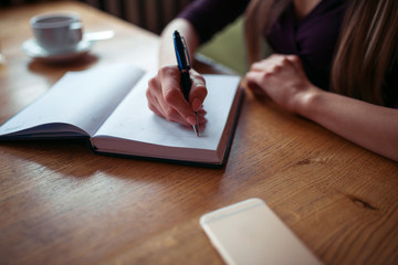 Fototapeta na wymiar Female hands writing in notebook closeup